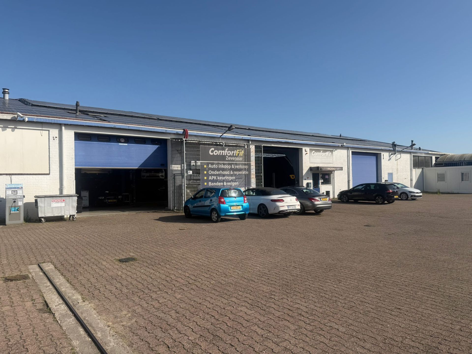 Vooraanzicht van de werkplaats van Comfort Fit Zevenaar met geparkeerde auto's